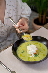 Woman is eating soup with seafood on a summer terrace of a fancy restaurant, close up, hands of a young woman