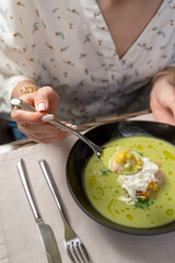 Woman is eating soup with seafood on a summer terrace of a fancy restaurant, close up, hands of a young woman