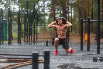 Full length photo of a man doing exercise lunges outdoors on a rainy day.