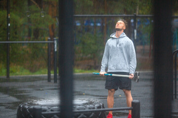 Portrait of a sportsman having rest after hard workout outdoor in a rainy day.