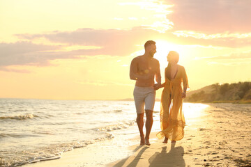 Fototapeta premium Happy young couple running together on beach at sunset