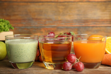 Glasses of delicious juices and fresh fruits on wooden table