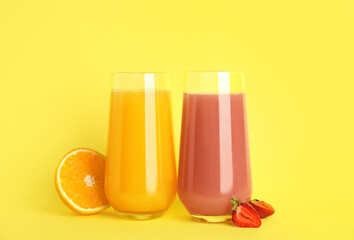 Glasses of delicious juices and fresh fruits on yellow background