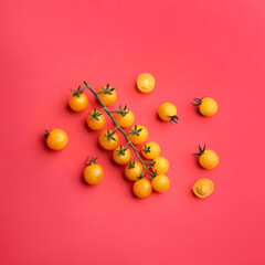 Yellow tomatoes on red background, flat lay