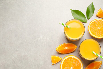 Glasses of orange juice and fresh fruits on light grey table, flat lay. Space for text