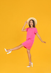 Fototapeta na wymiar Young woman wearing stylish pink dress on yellow background