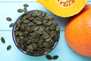 Peeled seeds and fresh pumpkin on light blue wooden table, flat lay