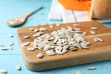 Raw pumpkin seeds on light blue wooden table, closeup