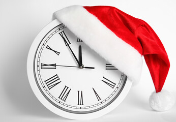 Clock with Santa hat showing five minutes until midnight on white background. New Year countdown