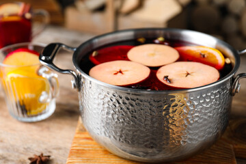 Delicious mulled wine and ingredients on wooden table, closeup