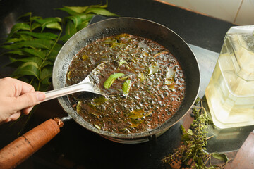 Home made ayurvedic Oil or Herbal Hair Oil preparation with Herbs neem leaves , amla berry , amla powder , aloe vera in coconut oil Indian  Ayurveda treatment for hair and skin medicine making. 