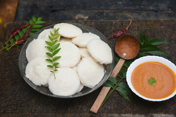 Indian idly served on traditional vegetarian food. Lots of many fresh steamed Indian Idly , Idli rice cake. South Indian breakfast idly sambar or Sambhar red coconut chutney