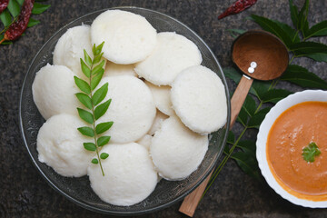 Indian idly served on traditional vegetarian food. Lots of many fresh steamed Indian Idly , Idli rice cake. South Indian breakfast idly sambar or Sambhar red coconut chutney
