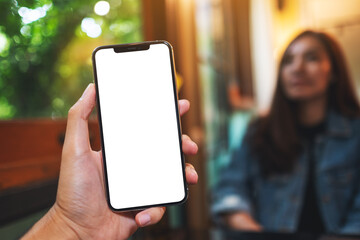 Mockup image of a man holding mobile phone with blank white screen with a woman in background