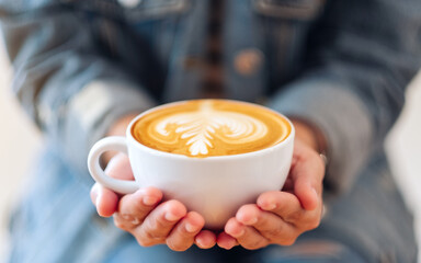 Closeup image of a woman holding a white cup of coffee