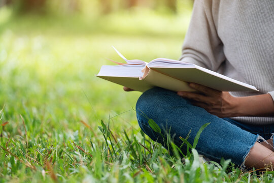 Closeup image of a woman reading a book while sitting in the park