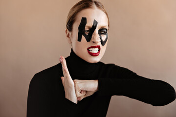 Irritated woman dressed in black outfit posing on black background. Girl with red lips and word no...