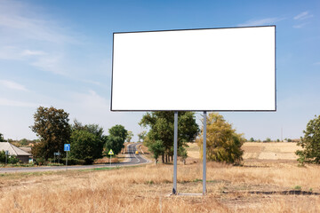 Empty billboard for advertising poster near asphalting road and village. Background of blue sky and beautiful nature.