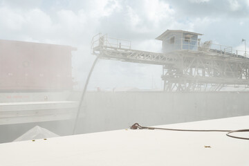 Loading of ship cargo gold with bulk cargo bauxite. Dusty atmosphere.