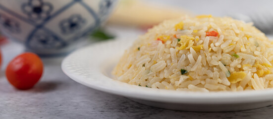 Fried rice in a white plate on a cement floor.