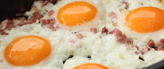 several fried eggs with bacon in the pan