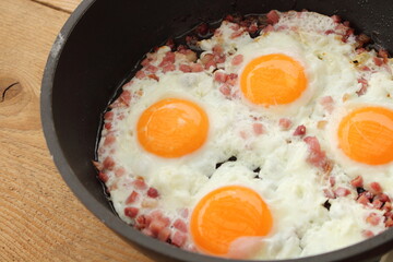 several fried eggs with bacon in the pan