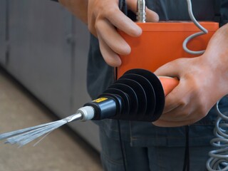 An employee sets up a spark flaw detector . Part of the image is blurred.