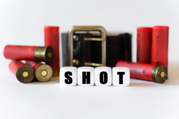 Against the background of cartridges and a military belt, cubes with the inscription - SHOT