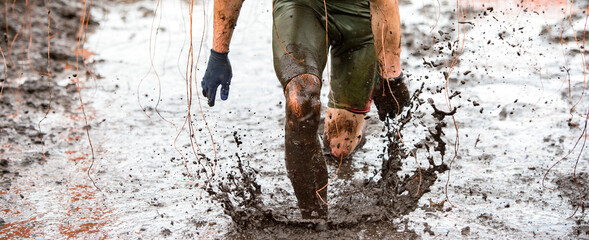 Mud race runner, man running in mud. Runners during extreme obstacle races. Active life and sport concept..