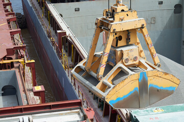 Fototapeta na wymiar Loading and dischargind operation of bulk cargo bauxite on bulk carrier ship using grab bucket