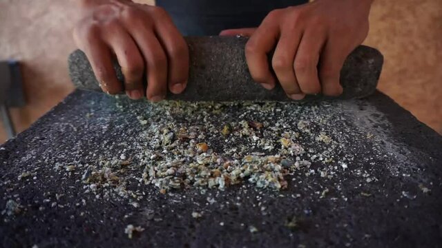 
grinding corn grains into metate, traditional way of making tortilla dough, traditional Mexican food