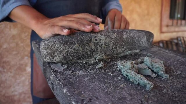 
grinding corn grains into metate, traditional way of making tortilla dough, traditional Mexican food