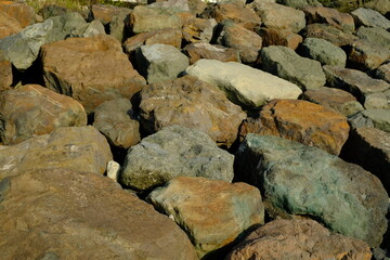 Background from a stone of igneous rock. Wallpaper made of textures of boulders of volcanic origin. Surface of granite, diabase, gabbro interspersed with spar, quartz. Sea shore. Day. Georgia.