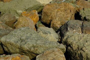 Background from a stone of igneous rock. Wallpaper made of textures of boulders of volcanic origin. Surface of granite, diabase, gabbro interspersed with spar, quartz. Sea shore. Day. Georgia.