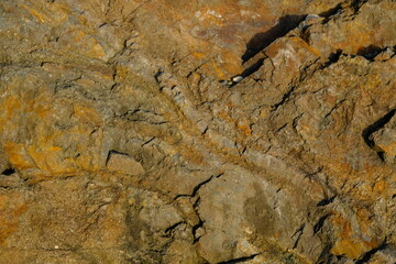 Background from a stone of igneous rock. Wallpaper made of textures of boulders of volcanic origin. Surface of granite, diabase, gabbro interspersed with spar, quartz. Sea shore. Day. Georgia.