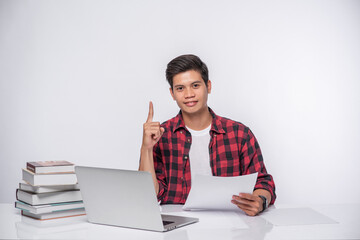 A man using a laptop in the office and doing a document analysis.