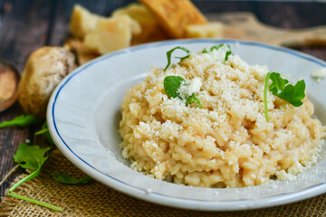 Italian creamy  cheese risotto with parmesan cheese and fresh basil on rustic background