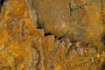 Background from a stone of igneous rock. Wallpaper made of textures of boulders of volcanic origin. Surface of granite, diabase, gabbro interspersed with spar, quartz. Sea shore. Day. Georgia.