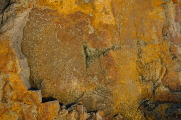 Background from a stone of igneous rock. Wallpaper made of textures of boulders of volcanic origin. Surface of granite, diabase, gabbro interspersed with spar, quartz. Sea shore. Day. Georgia.