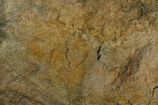 Background from a stone of igneous rock. Wallpaper made of textures of boulders of volcanic origin. Surface of granite, diabase, gabbro interspersed with spar, quartz. Sea shore. Day. Georgia.
