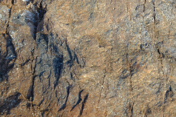 Background from a stone of igneous rock. Wallpaper made of textures of boulders of volcanic origin. Surface of granite, diabase, gabbro interspersed with spar, quartz. Sea shore. Day. Georgia.