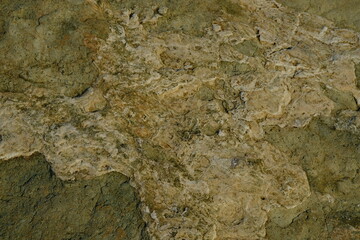 Background from a stone of igneous rock. Wallpaper made of textures of boulders of volcanic origin. Surface of granite, diabase, gabbro interspersed with spar, quartz. Sea shore. Day. Georgia.