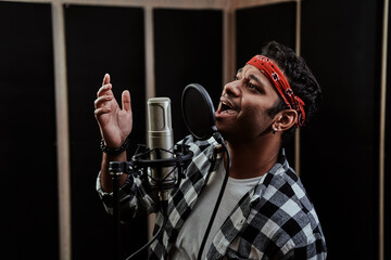 Portrait of young man, hip hop artist enjoying the process of singing into a condenser microphone...