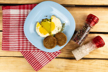 Top view of sliced fried egg on blue plate with croutons of bread