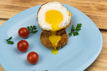 Top view of fried egg with crouton, cherry tomatoes on blue plate