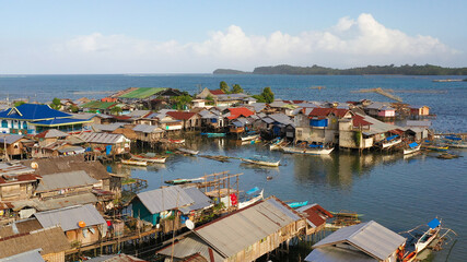 Fototapeta na wymiar Fishing village with wooden houses on stilts in the sea. Village of fishermen with houses on the water, with fishing boats. Philippines, Mindanao.