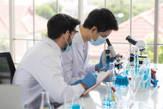 Health care researchers working in life science laboratory. Male research scientist and supervisor preparing and analyzing microscope slides in research lab. Invention of the coronavirus vaccine
