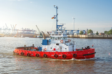 Red tugboat on the Elbe river in front of the harbour facilities in Hamburg, Germany