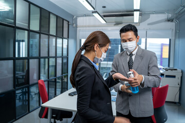 Business people with face mask protect from Coronavirus or COVID-19 are disinfecting hands at office after covid-19 quarantine and lockdown.