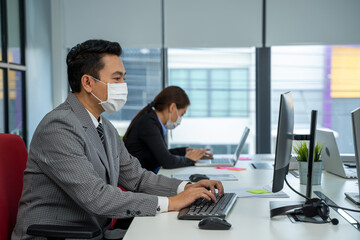 Obraz premium Businessman working and wear mask for protect Covid-19 or corona virus disease at model office,Healthcare concept.